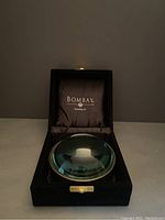 Magnifying dome in blue velvet box shown from above.