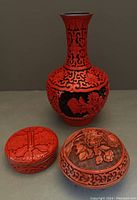 Full view of one vase and two small lidded containers, showing overall design and condition
