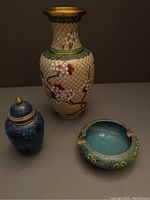Photo showing beige vase, blue covered jar with lid, and blue ashtray on a gray surface, highlighting overall lot contents