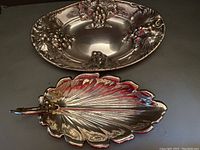 Silver plate grape leaf shaped tray showing textured leaf veins and handle extending from the stem end.