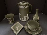 Shows complete set of 6 green Wedgwood Jasperware pieces including pitcher, cup and saucer, two vases, bud vase, and small tray.