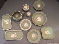Full set of 10 green Jasperware items arranged showing various plates, trays, cup, and covered jar with classical white relief decoration.
