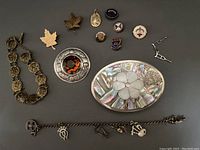 Full lot view showing all jewelry items arranged on flat surface including bracelet, belt buckle, brooch, pins, and badges.