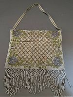 Front view of vintage steel beaded purse showing geometric lattice and floral corner design with tassels.