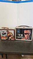 Both lunch boxes side by side on a black surface, displaying front artwork clearly.