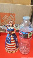 Photo of the Jim Shore Patriotic Angel figurine next to a water bottle for scale.