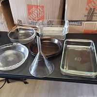 Full set of six Pyrex kitchen items placed on a table, showing brown and clear glassware including baking dishes and a funnel.