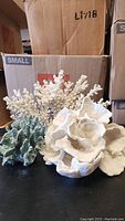 Three coral ornaments displayed on a black surface with a cardboard box in the background.