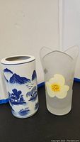 Two flower vases side by side, Japanese porcelain vase with blue landscape on left, frosted Murano glass vase with yellow flower on right.