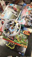 Photo showing LEGO Star Wars box and a plastic container filled with assorted loose LEGO pieces including grey mechanical parts and minifigure parts.