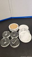 Photo showing six marble coasters stacked with one turned to show cork bottom, and four clear glass fermentation weights in front.