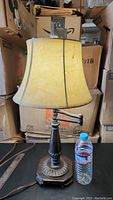 Full view of the swing arm lamp with beige shade and wooden base. Shade shows some imperfections and discoloration.