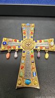 Close-up of the front side of the jewel encrusted cross showing multiple colored stones and hanging beads