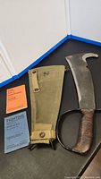 Top-down overview showing machete blade, scabbard and both manuals