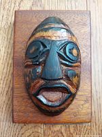 Front view of wooden carved First Nations mask mounted on plaque, showing signature D.A. Louie.