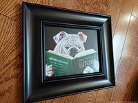 Framed bulldog print leaning against a wooden floor, showing the full frame and artwork.