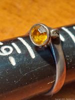 Close-up front view of vintage sterling silver ring with round amber gemstone on measuring stick showing size 8.