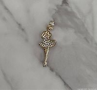 Single gold tone ballerina brooch on a marble background