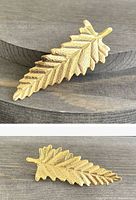 Photo showing front and back side of the gold tone leaf-design brooch on wooden surface.