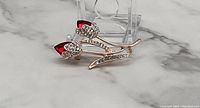 Rose gold tone red flower brooch with two red petal stones and clear rhinestone accents on petals and stem.