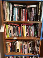 Photo showing three shelves of a wooden bookshelf filled with books on military topics, special forces, espionage fiction, film and sports.