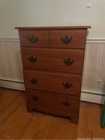 Front view of the wooden four drawer dresser showing all drawers and metal handles.