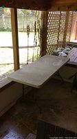 Side view of beige plastic folding table with metal legs, showing length and surrounding area.