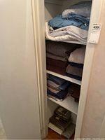 Full view of shelving closet with stacks of folded sheets, towels and curtains.