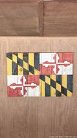Front view of the wooden Maryland flag wall art showing the full flag design on wooden planks attached horizontally with some weathered paint.