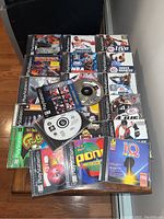 Overview of multiple PlayStation One game discs and cases including sports titles and arcade games like Frogger and Pong.