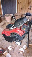 Red Toro Power Clear 210 R snow blower with some parts disconnected and resting on top and around it in a shed.
