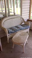 White wicker bench with blue cushion and matching white wicker coffee table shown together.
