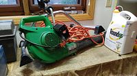 Sears electric blower with orange cord next to a container of Roundup weed killer on a workbench