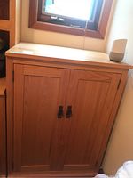 Front view of solid wood cabinet with two doors and brass drop pull handles beneath a window.