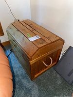 Angled view of pine wood chest showing rope handle on side and slatted top panels.