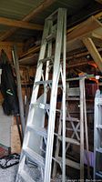 Full view of the 8' aluminum stepladder leaning inside a shed showing multiple wide steps and Caradon Ltd label