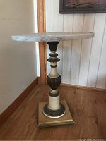 Side view showing the full round marble top and decorative pedestal base of the table.