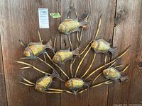 Front view of metal wall art showing fish and underwater plants attached to wooden background.