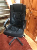 Front view of black faux leather office chair showing padded backrest, seat, and armrests.