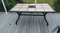 Full view of aluminum patio dining table with tiled surface on a deck