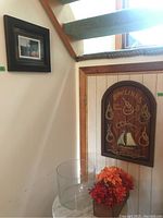 View of entire lot with rope knot art on wall, round glass vase, faux floral arrangement, and framed photo.