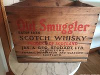 Front and sides view of Old Smuggler Scotch Whisky wooden crate showing branding and condition.