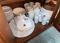 Johnson Brothers white ironstone dishes including mugs, salt and pepper shakers, covered serving dish with wooden lid inside a wooden cabinet.