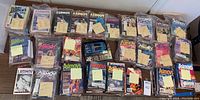 Wide view of approx. 30 Isaac Asimov's Science Fiction magazines, mostly in plastic bags, arranged in rows on a table with handwritten sticky notes indicating years and issue numbers.