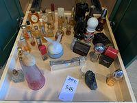 Full view of assorted cologne and perfume bottles shown in a drawer. Includes multiple brands, shapes, and sizes with some labels visible including Avon Wild Country, First Class Male, and others.