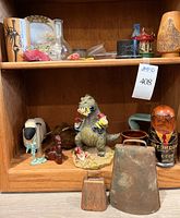 Wooden shelf with Godzilla figurine eating gnomes, nesting dolls, cow bells, small carousel, and other items