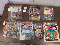 Six zip-lock bagged comics on table including Fantastic Four, Doctor Strange, Iron Man, Sub-Mariner, The Defenders and Treasury Edition