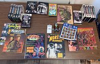 Full view of all items including Addams Family VHS, DVDs, magazines, and stamp sheet.