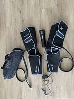 Full view of Lifepro Radiate compression sleeves for right and left legs laid out with wired remote controller and black carrying bag.