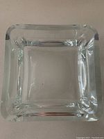 Clear square solid glass bowl with thick walls and smooth edges, photographed from above